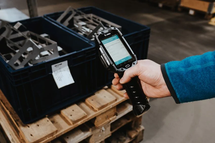 Lagermitarbeiter%20scannt%20Lagerbeh%E4lter%20mit%20einem%20Android-Handheld%20und%20SAP-Logistik-App%20als%20Teil%20der%20mobilen%20L%F6sung%20von%20MKN%20f%FCr%20verbesserte%20Bestandsf%FChrung%20und%20Kanban-Management.